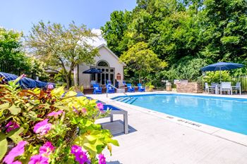 a swimming pool with a white house and blue umbrellas in the background